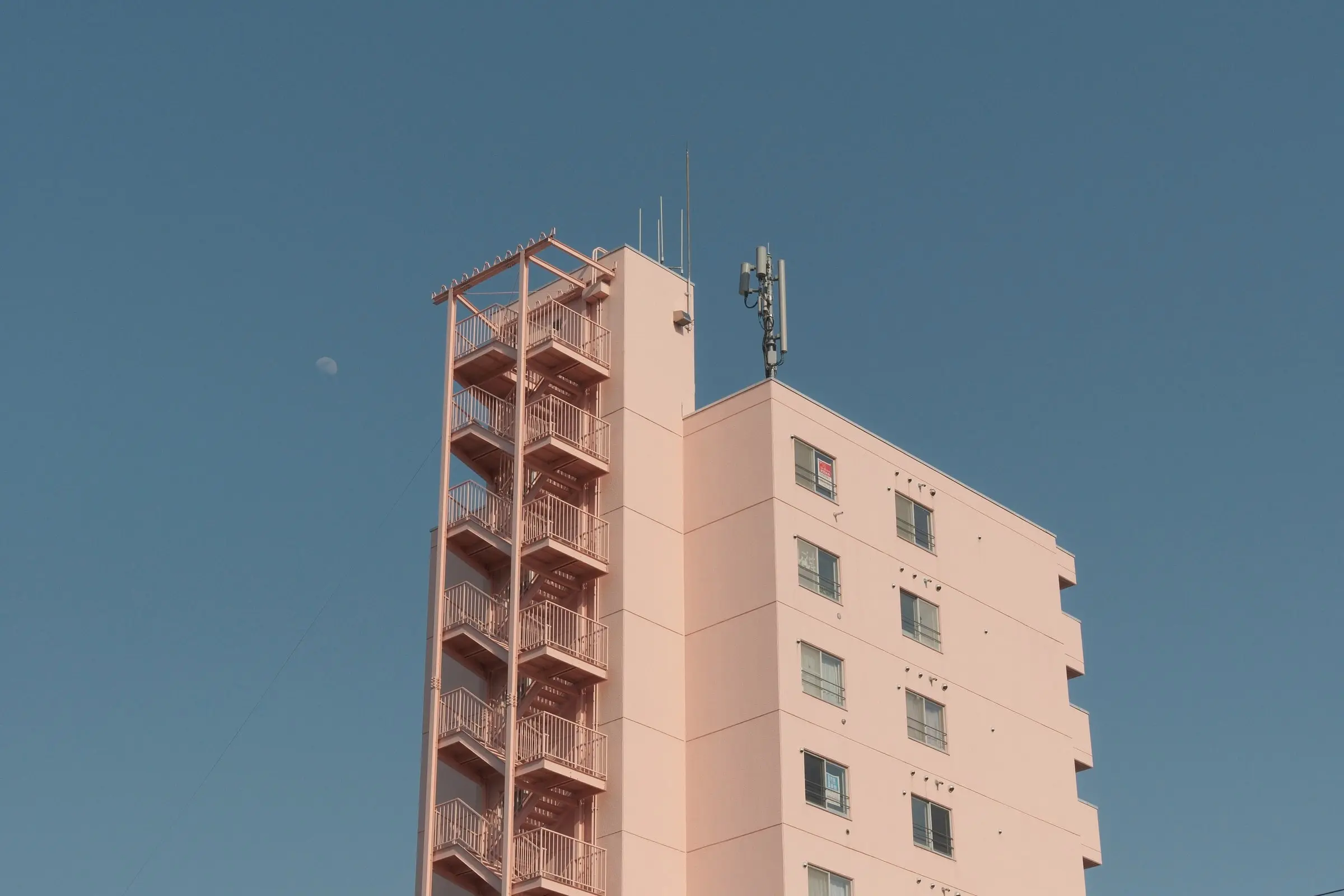 A pink building with an external staircase — Asahikawa
