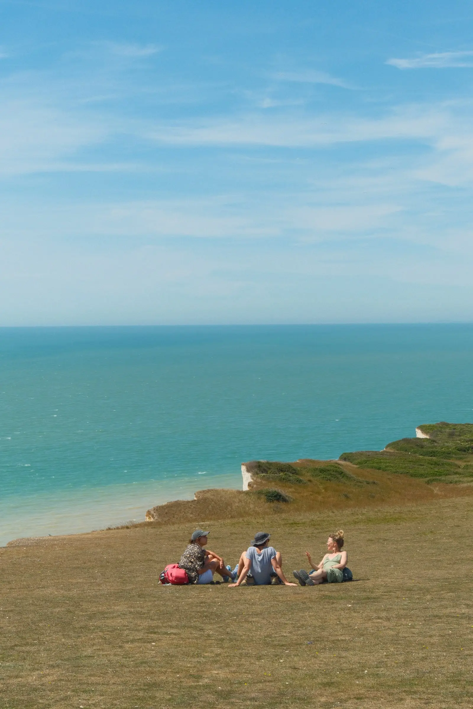 Friends picnicking on a clifftop above turquoise water — Seven Sisters
